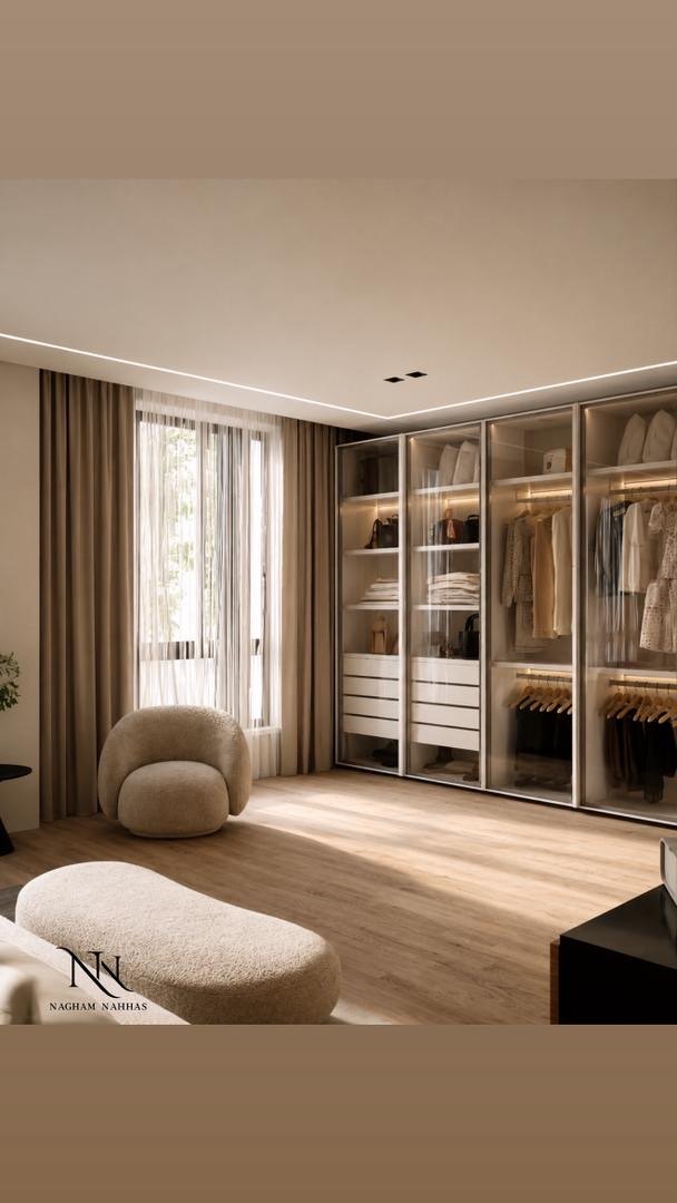 Dressing room with glass-fronted wardrobes, lit rails and a bouclé armchair